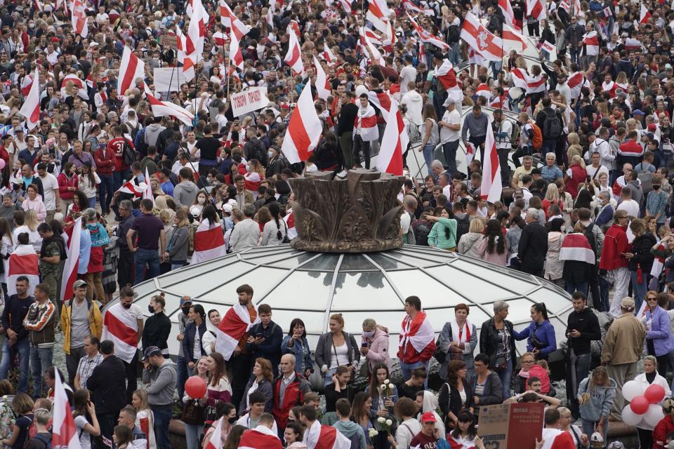 Belarusian opposition supporters with old Belarusian national flags rally at Independence Square in Minsk, Belarus, Sunday, Aug. 23, 2020. A vast demonstration with many thousands of protesters demanding the resignation of Belarus' authoritarian president are rallying in the capital, continuing the public dissent since the disputed presidential election. (AP Photo/Evgeniy Maloletka)