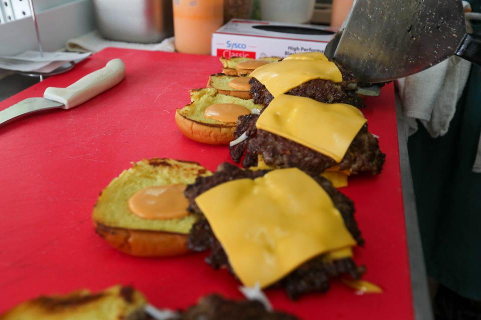 Chef Steffan Rost prepares a row of Smash Burgers at the Crispi food truck at Two Tides Brewing Company on West 41st Street.