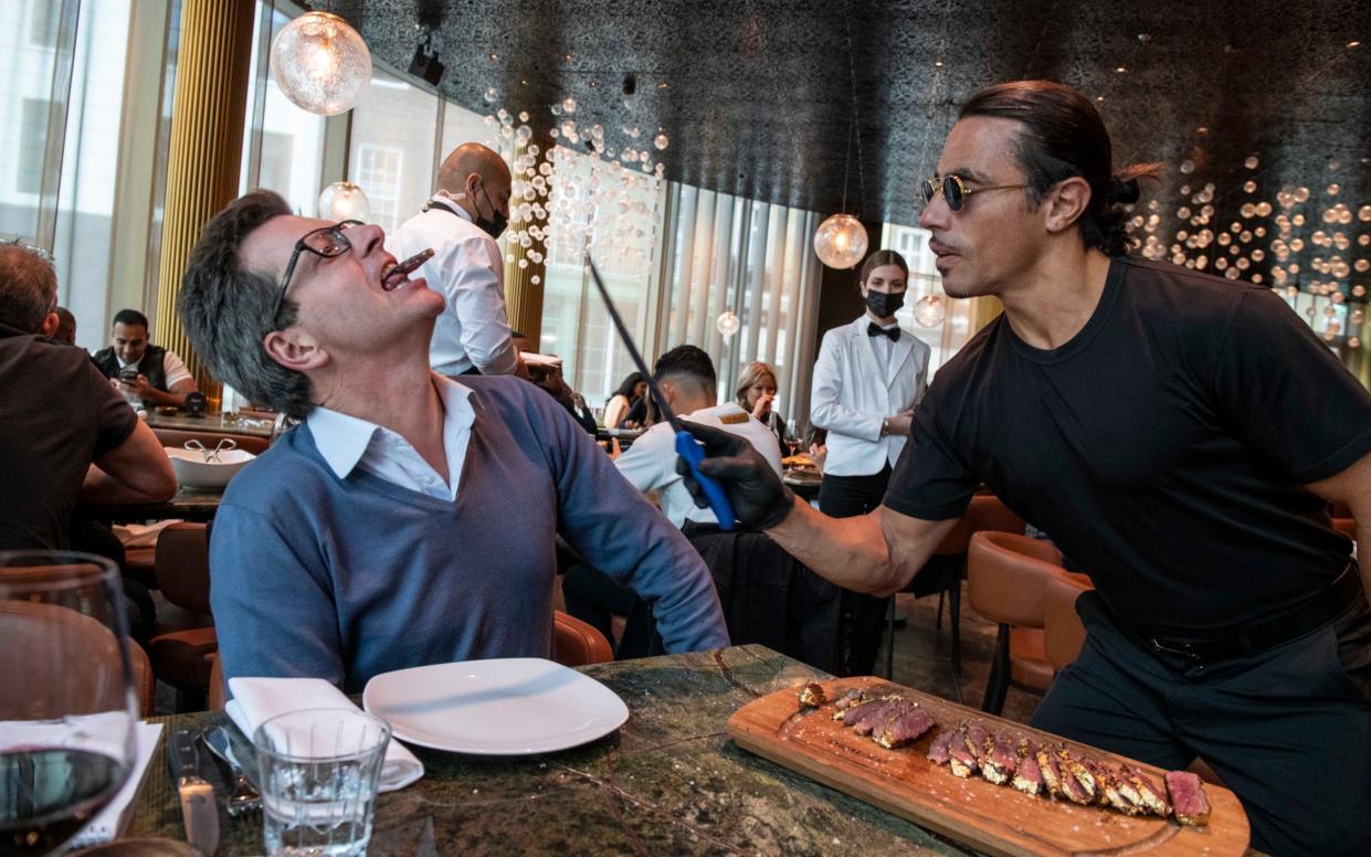 Turkish butcher chef and restaurateur Nusret Gokce, known as Salt Bae, prepares a steak for The Telegraph's William Sitwell