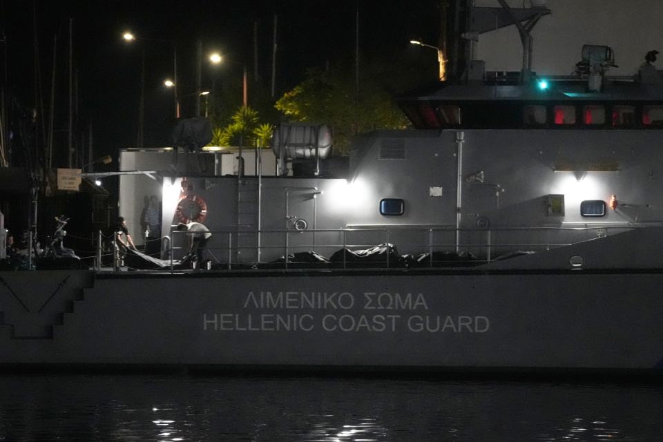 Rescue workers carry bodies from a coast guard vessel to a refrigerated truck at the port in Kalamata town, about 240 kilometers (150 miles) southwest of Athens late Wednesday, June 14, 2023. An overcrowded fishing boat carrying migrants capsized and sank off the coast of Greece, leaving dozens of people dead and many more missing in one of the worst disasters of its kind this year. (AP Photo/Thanassis Stavrakis)