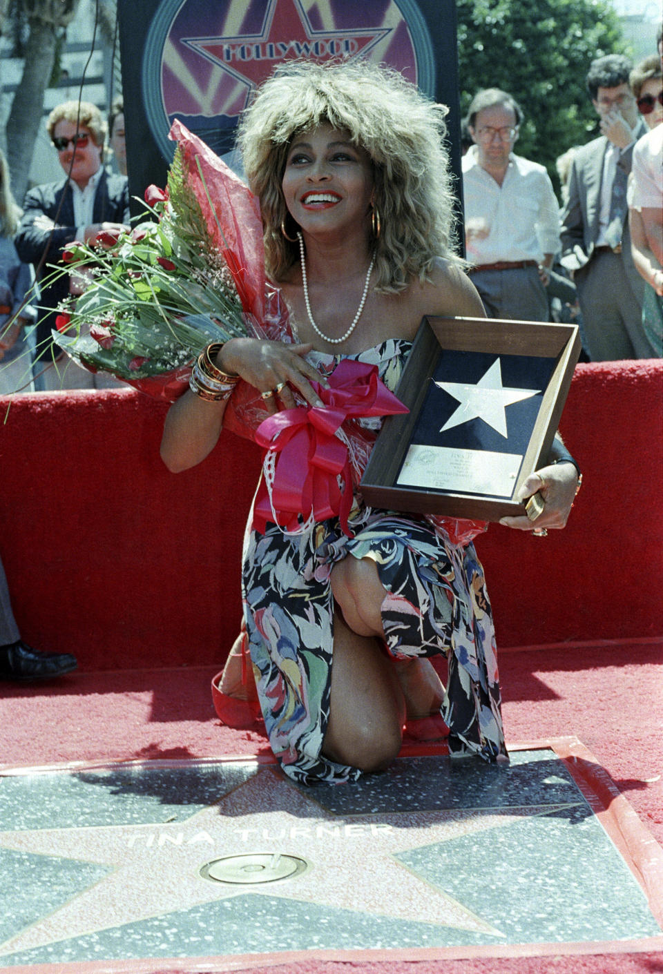 ARCHIVO - Tina Turner posa con su placa y un ramo de flores cerca de su estrella en el Paseo de la Fama de Hollywood, durante la ceremonia de revelación de la placa el 28 de agosto de 1986, en Los Ángeles. (AP Foto/Nick Ut, Archivo)