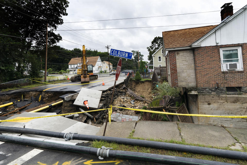 Police caution tape is stretched in front of a home where the front yard and road were washed away by recent flooding, Wednesday, Sept. 13, 2023, in Leominster, Mass. (AP Photo/Robert F. Bukaty)