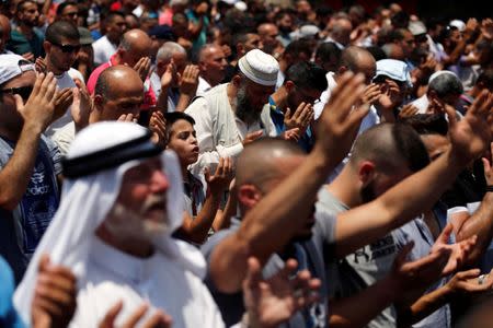 Palestinians pray on a street near a road block outside Jerusalem's Old city July 21, 2017. REUTERS/Amir Cohen