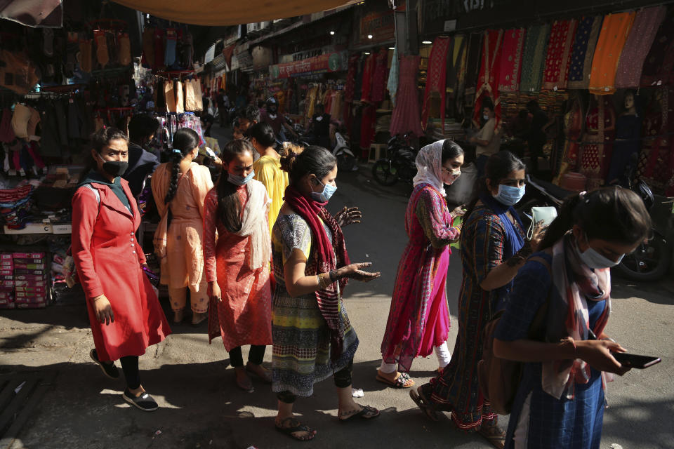 People wearing masks as a precaution against the coronavirus shop at a market ahead of Hindu festivals in Jammu, India, Thursday, Oct.29, 2020. India's confirmed coronavirus caseload surpassed 8 million on Thursday with daily infections dipping to the lowest level this week, as concerns grew over a major Hindu festival season and winter setting in. (AP Photo/Channi Anand)