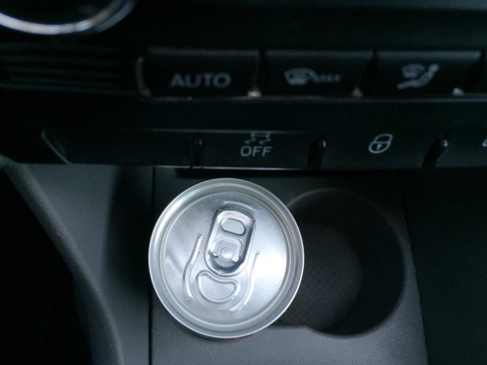 A canned beverage in a car's center cup holder.