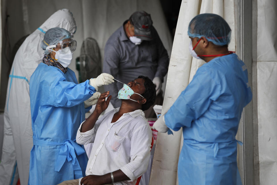 Health workers conduct COVID-19 antigen tests for migrant workers in New Delhi, India, Aug. 18, 2020. In June, India began using the cheaper, faster but less accurate tests to scale up testing for the coronavirus — a strategy that the U.S. is now considering. (AP Photo/Manish Swarup)