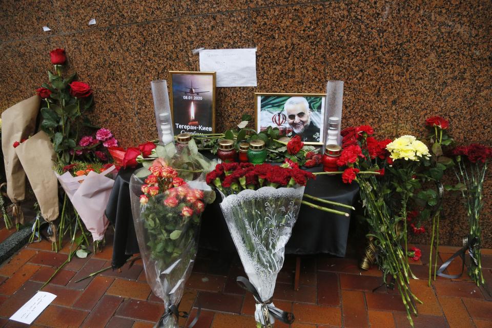 Flowers and tributes are placed outside the Iranian Embassy in Kyiv, Ukraine, Friday, Jan. 10, 2020, with a poster that reads: "Tehran - Kyiv, we're mourning" for the victims of the Ukrainian 737-800 plane that crashed on the outskirts of Tehran, Iran, and a photo of Iranian Revolutionary Guard Gen. Qassem Soleimani who was killed by U.S. airstrike in Iraq. Iran on Friday denied Western allegations that one of its own missiles downed a Ukrainian jetliner that crashed outside Tehran, and called on the U.S. and Canada to share any information they have on the crash, which killed all 176 people on board. (AP Photo/Efrem Lukatsky)