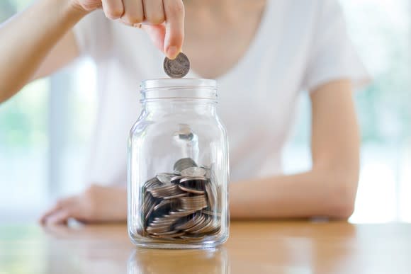 Woman dropping a coin into a savings jar