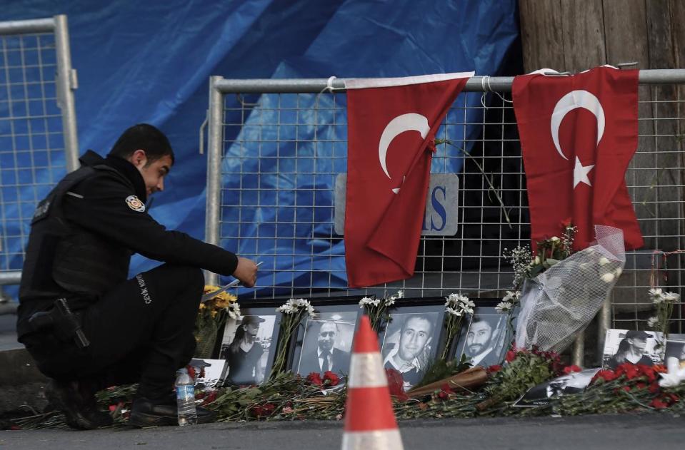 A police officer looks a photographs of the victims displayed a day after an attack at a popular nightclub in Istanbul, Monday, Jan. 2, 2017. A manhunt is on in Turkey as authorities work to identify the assailant who killed dozens of people in a crowded Istanbul nightclub during New Year's celebrations Sunday.(AP Photo/Halit Onur Sandal)
