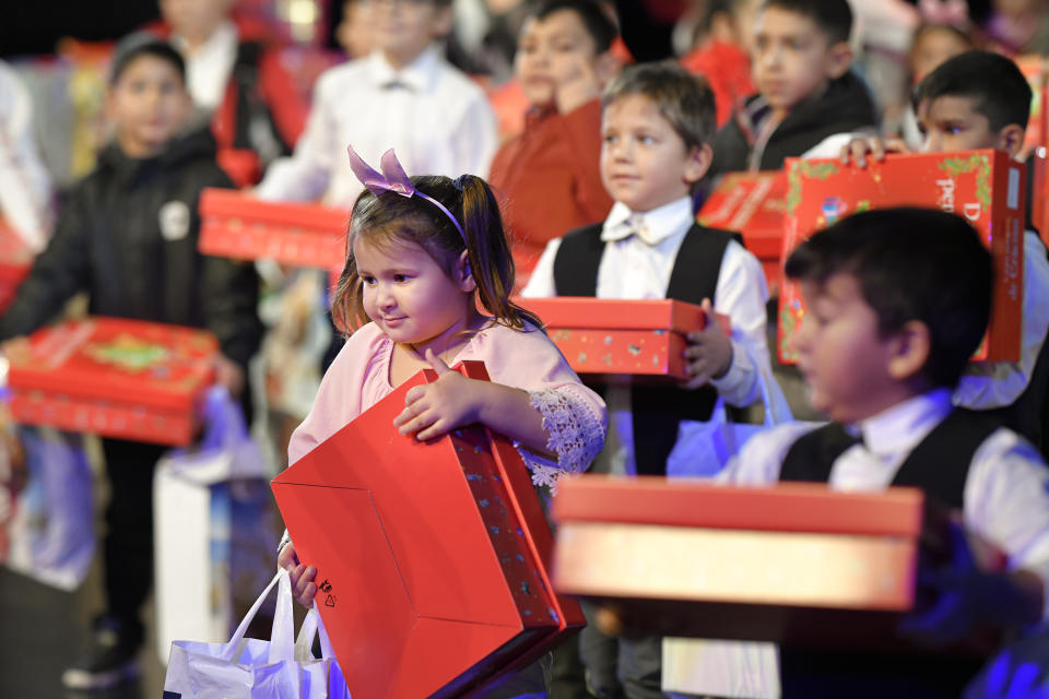 Children hold presents received after a Christmas show for children in care, in Bucharest, Romania, Wednesday, Dec. 18, 2019. Romania has more than 50 thousand children in state care, according to recent statistics quoted by local media. (AP Photo/Andreea Alexandru)