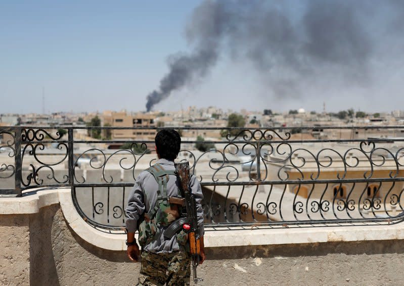 FILE PHOTO: A Kurdish fighter from the People's Protection Units (YPG) looks at a smoke after an coalition airstrike in Raqqa, Syria June 16, 2017. REUTERS/Goran Tomasevic/File Photo