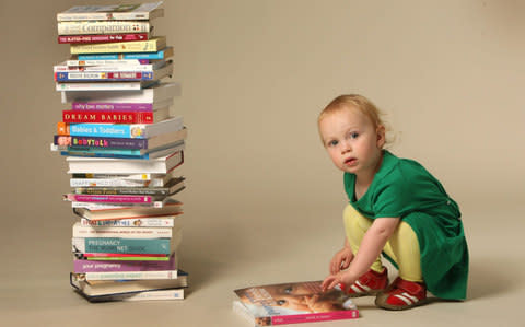 Young toddler with a stack of baby books - Credit: Martin Pope