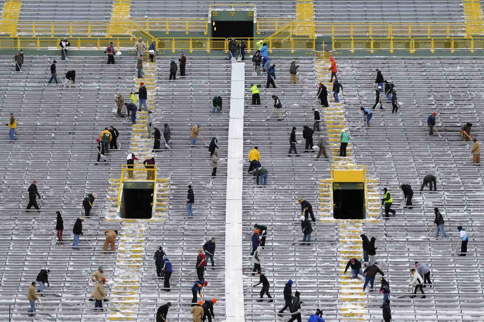 Paid volunteers clear snow from the bleachers at Lambeau Field in Green Bay, Wisconsin, the home field of the Green Bay Packers of the National Football League (NFL), December 21, 2013. In winter months, the team calls on the help of hundreds of citizens, who also get paid a $10 per-hour wage, to shovel snow and ice from the seating area ahead of games, local media reported. The Packers will host the Pittsburgh Steelers on Sunday, December 22. REUTERS/Mark Kauzlarich (UNITED STATES - Tags: ENVIRONMENT SPORT FOOTBALL TPX IMAGES OF THE DAY)