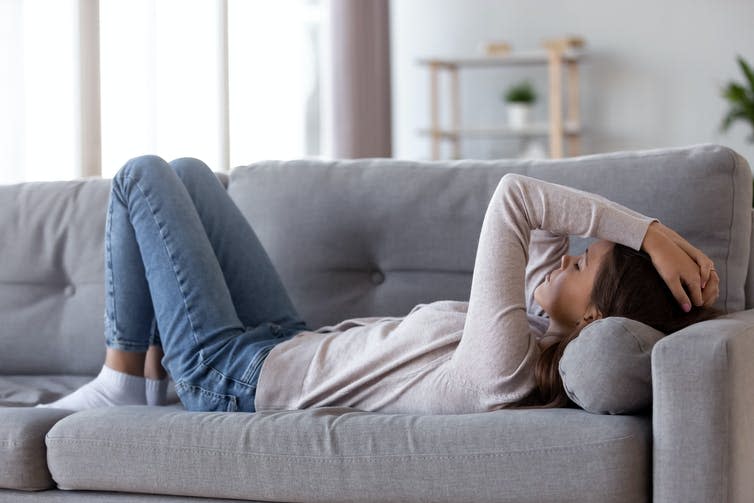 A teenage girl suffering from long COVID lying on a sofa