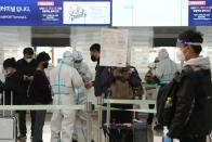 Staff members wearing protective gear guide passengers at the Incheon International Airport In Incheon, South Korea, Wednesday, Dec. 1, 2021. South Korea's daily jump in coronavirus infections exceeded 5,000 for the first time since the start of the pandemic, as a delta-driven surge also pushed hospitalizations and deaths to record highs. (AP Photo/Ahn Young-joon).
