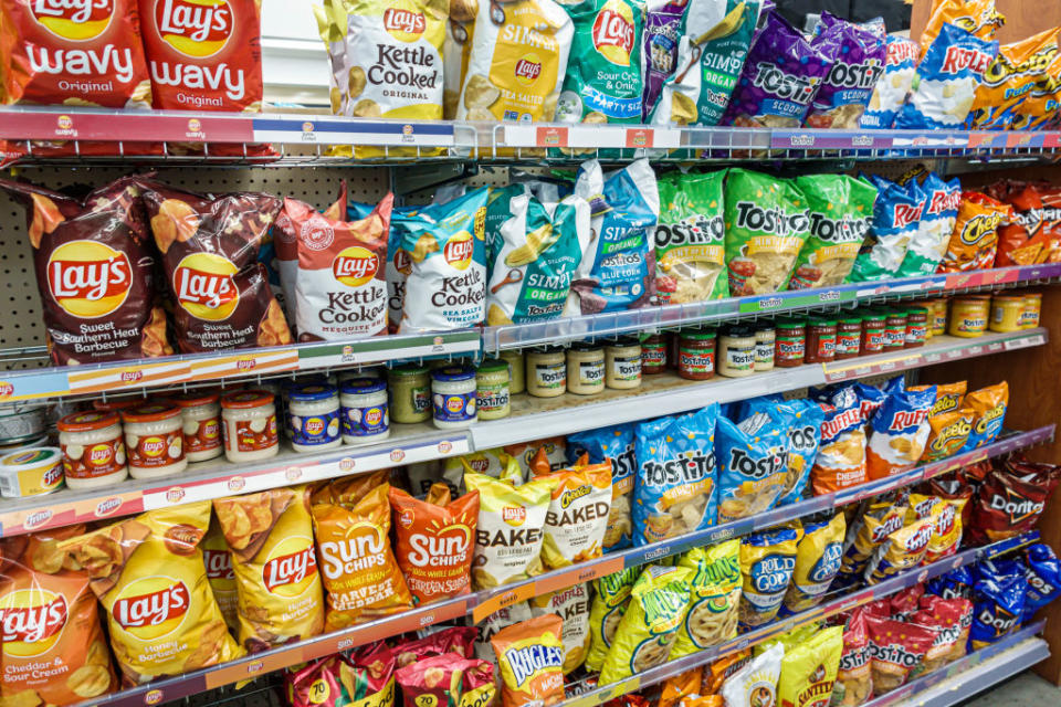 Aisle in a store with assorted brands of chips and jarred dips on shelves