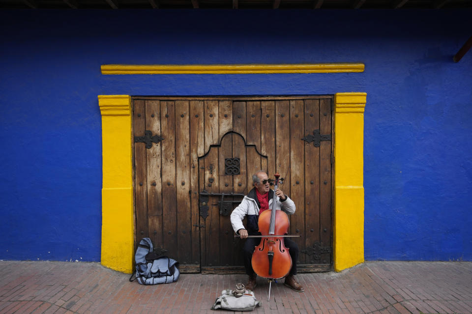 Fabio Guarin, 76, plays a cello for tips which he said he uses to buy his meals in the La Candelaria neighborhood of Bogota, Colombia, Thursday, Aug. 4, 2022. Guarin said he used to earn money playing in an amateur band known as a "toque," hired for bars and private events. (AP Photo/Fernando Vergara)