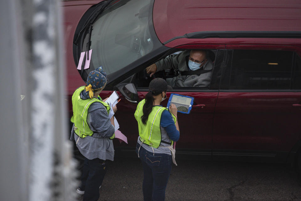 Volunteers take down information as they register people to receive the Pfizer COVID-19 vaccine at the vaccination clinic put on by the City of Odessa, Odessa Fire Rescue and Medical Center Hospital Sunday, Jan. 24, 2021 at Ratliff Stadium in Odessa, Texas. (Eli Hartman/Odessa American via AP)