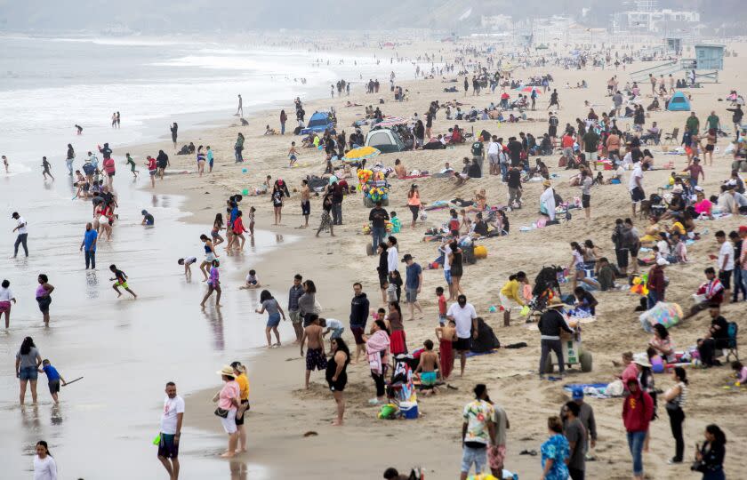 Santa Monica, CA - May 13: Beachgoers play in the sand and surf under gray skies at Santa Monica Pier Saturday, May 13, 2023 in Santa Monica, CA. Overcast skies may give way to sun and warmer weather soon. (Brian van der Brug / Los Angeles Times)