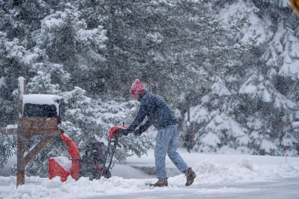 A man clears snow from his driveway Friday, March 22, 2024, in Mequon, Wisconsin. The National Weather Service is now projecting three to six inches of snow to fall in the Milwaukee area.