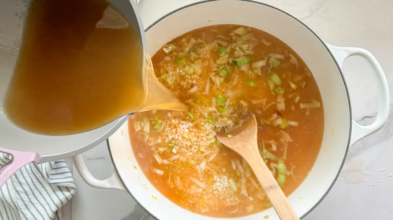 adding broth to pot