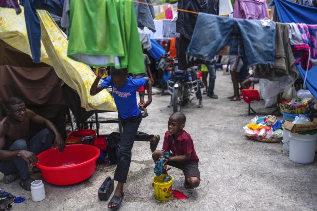 A youth washes clothes at a public school that serves as a shelter for people displaced from their homes due to clashes between armed gangs in Port-au-Prince, Haiti, Monday, April 22, 2024. (AP Photo/Ramon Espinosa)