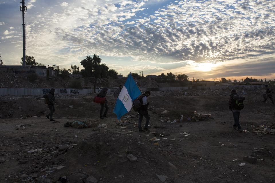 A man traveling with a Central American migrant caravan carries a Guatemalan flag at sunrise as the group leaves Mexicali for Tijuana, Mexico, Tuesday, Nov. 20, 2018. Tensions have built as nearly 3,000 migrants from the caravan poured into Tijuana in recent days after more than a month on the road, and with many more months likely ahead of them while they seek asylum in the U.S. (AP Photo/Rodrigo Abd)