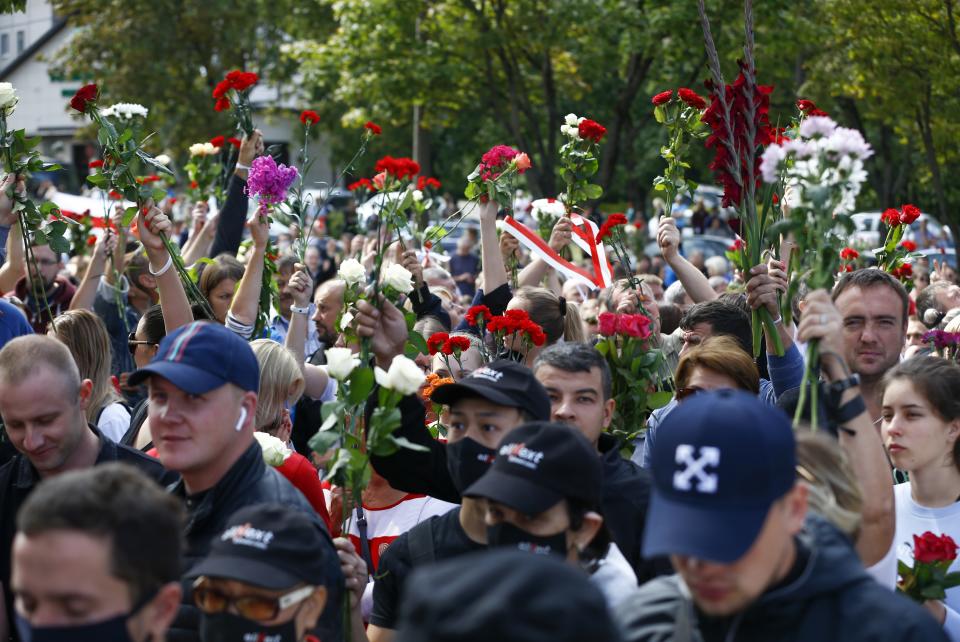 People wave flowers at the farewell hall during the funeral of Alexander Taraikovsky who died amid clashes protesting the election results, in Minsk, Belarus, Saturday, Aug. 15, 2020. Taraikovsky died Monday as demonstrators roiled the streets of the capital Minsk, denouncing official figures showing that authoritarian President Alexander Lukashenko, in power since 1994, had won a sixth term in office. (AP Photo/Sergei Grits)