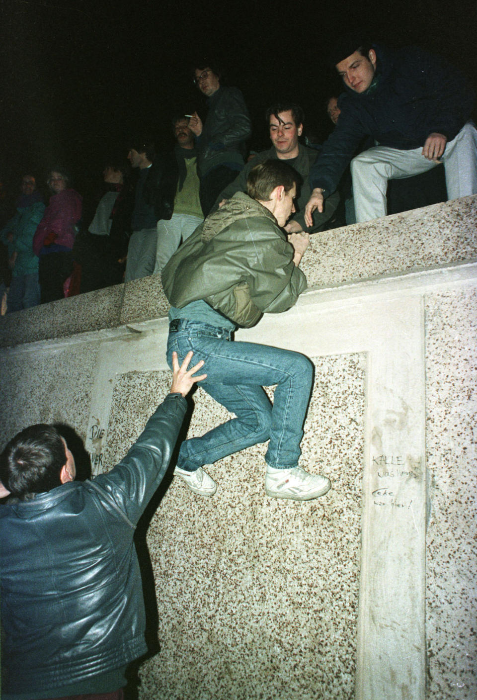 East German citizens help each other climb the Berlin Wall at the Brandenburg gate after the opening of East German borders in this early Nov. 10, 1989. (Photo: Reuters)