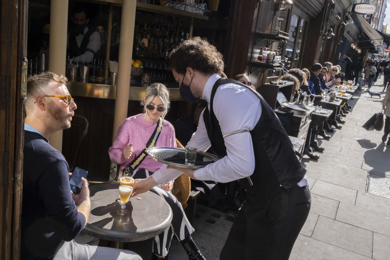 On the day that the UK government eased Covid restrictions to allow non-essential businesses such as shops, pubs, bars, gyms and hairdressers to re-open, customers are served outdoor drinks on Old Compton Street in Soho, on 12th April 2021, in London, England. (Photo by Richard Baker / In Pictures via Getty Images)