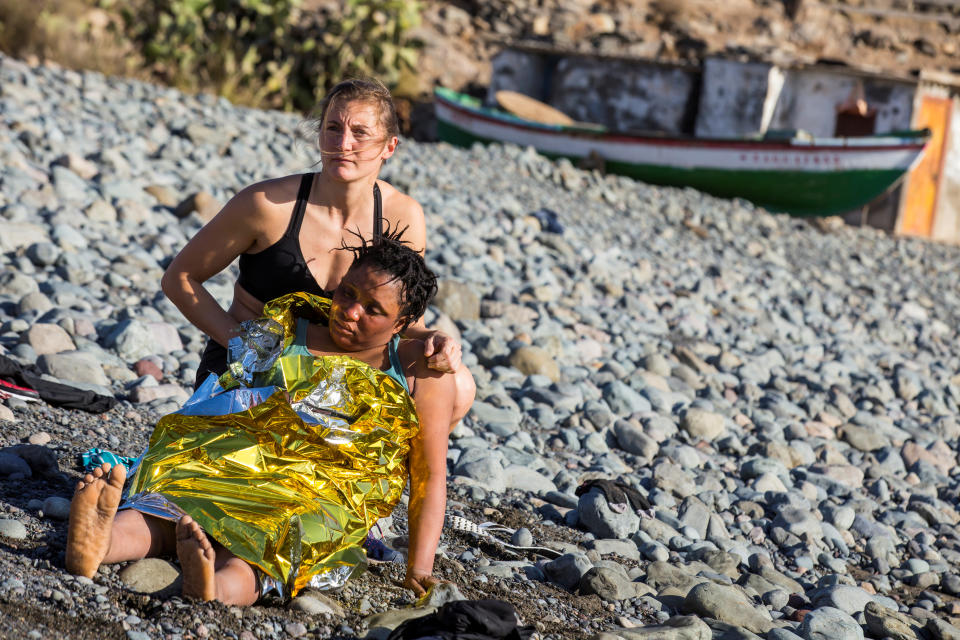 A beachgoer assists a woman.