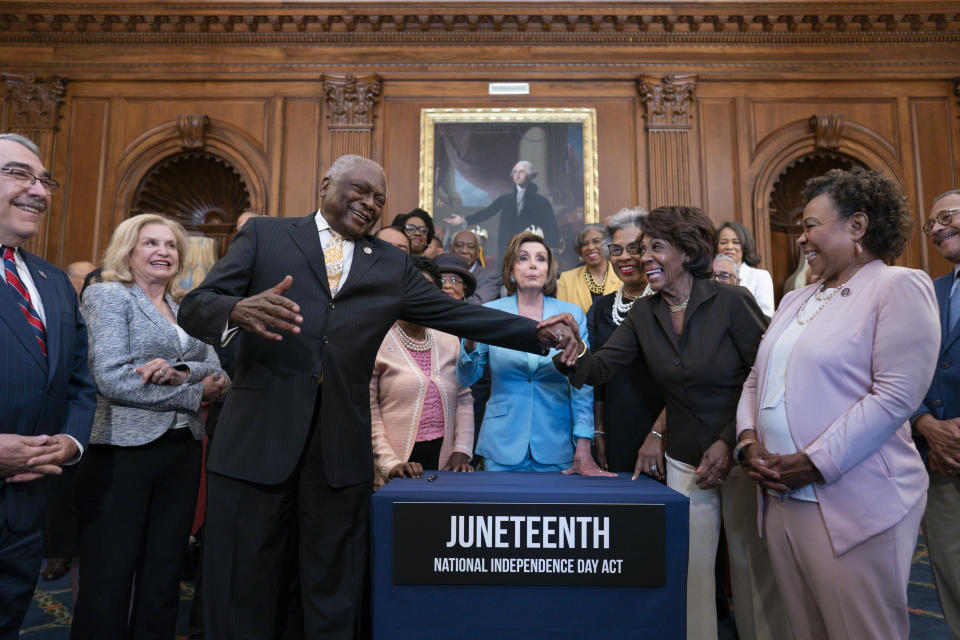 House Majority Whip James Clyburn, D-S.C., center left, reaches over to Rep. Maxine Waters, D-Calif., joined by Speaker of the House Nancy Pelosi, D-Calif., center, and members of the Congressional Black Caucus as they celebrate the Juneteenth National Independence Day Act that creates a new federal holiday to commemorate June 19, 1865, when Union soldiers brought the news of freedom to enslaved Black people after the Civil War, at the Capitol in Washington, Thursday, June 17, 2021. It's the first new federal holiday since Martin Luther King Jr. Day was created in 1983. (AP Photo/J. Scott Applewhite)