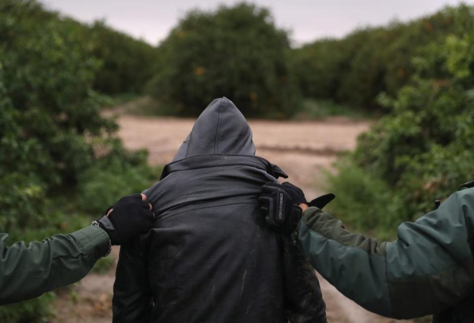 U.S. Border Patrol agents detain an undocumented immigrant from Central America after capturing his group in a grapefruit orchard on February 22, 2018 near McAllen, Texas. (Photo by John Moore/Getty Images)