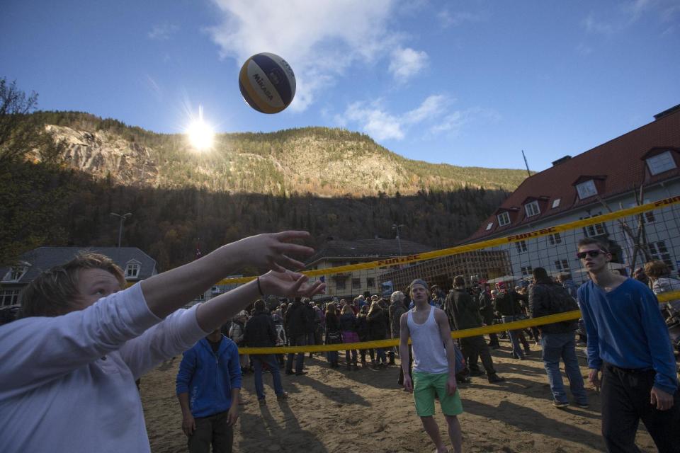 A group of youths play games after the official opening of giant sun mirrors in the town of Rjukan, Norway, Wednesday, Oct. 30, 2013. Residents of the small Norwegian town of Rjukan have finally seen the light. Tucked in between steep mountains, the town is normally shrouded in shadow for almost six months a year. But on Wednesday faint rays from the winter sun for the first time reached the market square thanks to three 183-square-foot (17-square-meter) mirrors placed on a mountain. (AP Photo/NTB Scanpix, Terje Bendiksby) NORWAY OUT