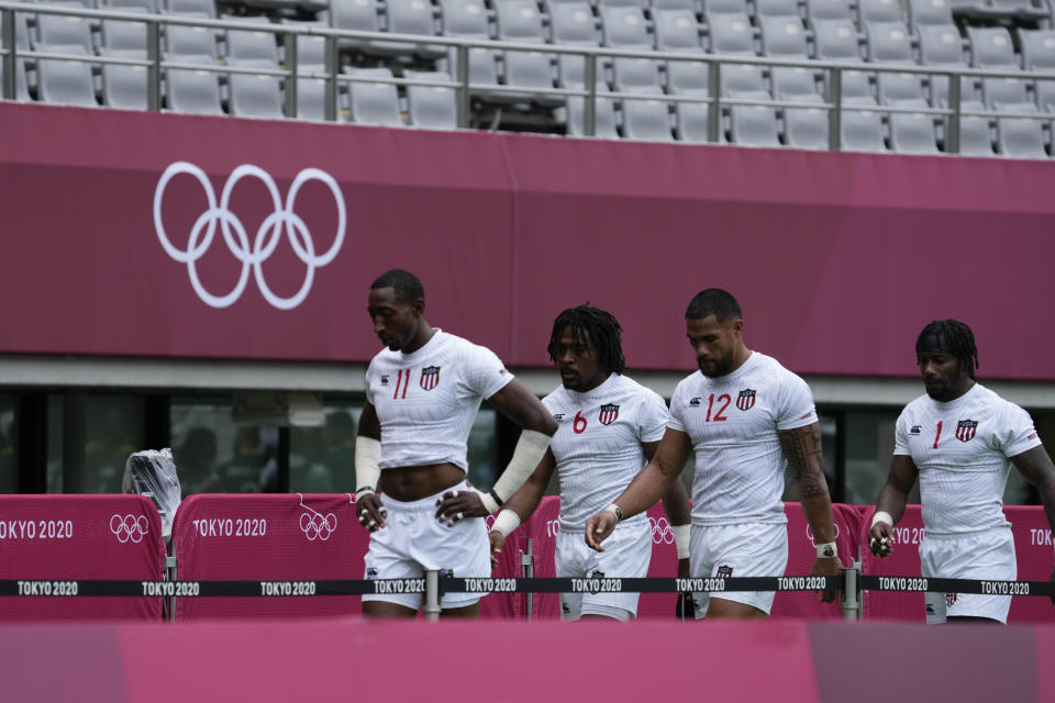 United States team members, from left, Perry Baker, Kevon Williams, Martin Iosefo, and Carlin Isles, walk off the pitch after losing their men's rugby sevens match against South Africa, at the 2020 Summer Olympics, Tuesday, July 27, 2021 in Tokyo, Japan. (AP Photo/Shuji Kajiyama)
