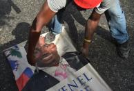 <p>Protesters destroy a poster of Haitian President Jovenel Moise as they demonstrate in the Port-au-Prince suburb of Petion-Ville on July 7, 2018, against a hike in fuel prices. (Photo: Hector Retamal/AFP/Getty Images) </p>