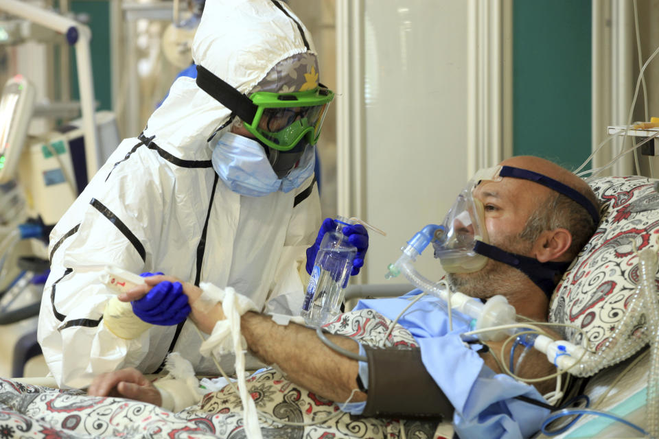 In this Wednesday, Oct. 14, 2020, photo provided by the Iranian Health Ministry, a medic tends to a COVID-19 patient at the Shohadaye Tajrish Hospital in Tehran, Iran. Iran is confronting a new surge of infections that is filling hospitals and cemeteries alike. (Akbar Badrkhani/Iranian Health Ministry via AP)