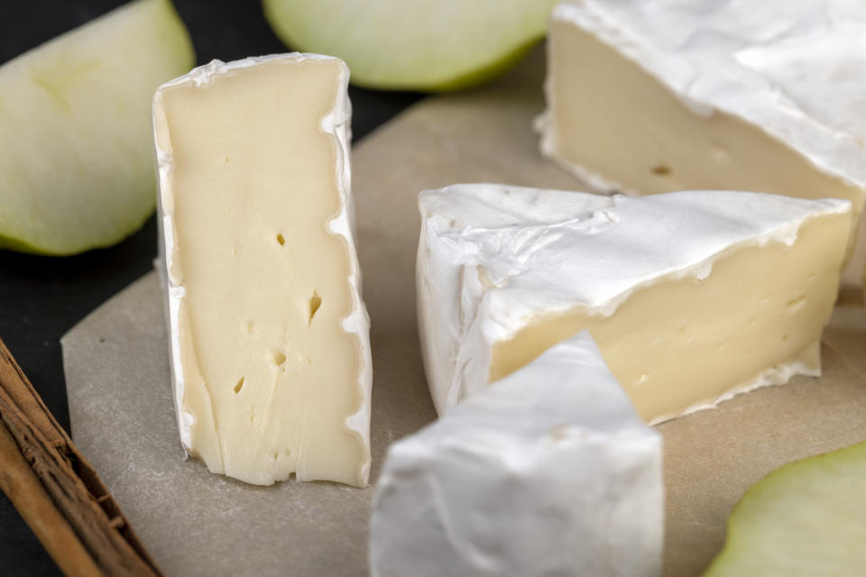 Close-up of sliced Brie cheese and pear wedges on parchment paper