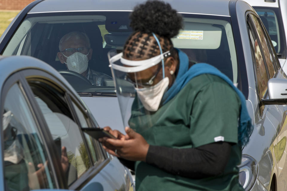 A health worker checks the documents of a senior getting vaccinated with the first dose of Pfizer's coronavirus vaccine at the newly-opened mass vaccination program for the elderly at a drive-thru vaccination center in Johannesburg, South Africa, Tuesday, May 25, 2021. South Africa aims to vaccinate 5 million of its older citizens by the end of June. (AP Photo/Themba Hadebe)