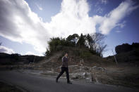 FILE - In this March 5, 2015, file photo, Michihiro Kono, president of Yagisawa Shoten Co., walks by a hill where his company's employees ran up to a shrine for safety when the 2011 tsunami hit Rikuzentakata, Iwate Prefecture, northeastern Japan. Just a month after a tsunami smashed into the city of Rikuzentakata, Kono took over his family's soy sauce business. (AP Photo/Eugene Hoshiko, File)