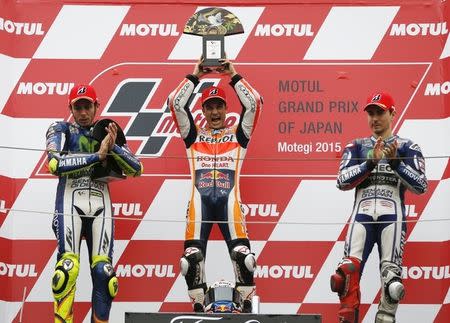 Honda MotoGP rider Dani Pedrosa (C) of Spain raises his trophy as he celebrates on the podium after winning the Japanese Grand Prix next to Yamaha MotoGP riders Valentino Rossi (L) of Italy and Jorge Lorenzo of Spain at the Twin Ring Motegi circuit in Motegi, north of Tokyo, Japan, October 11, 2015. REUTERS/Issei Kato