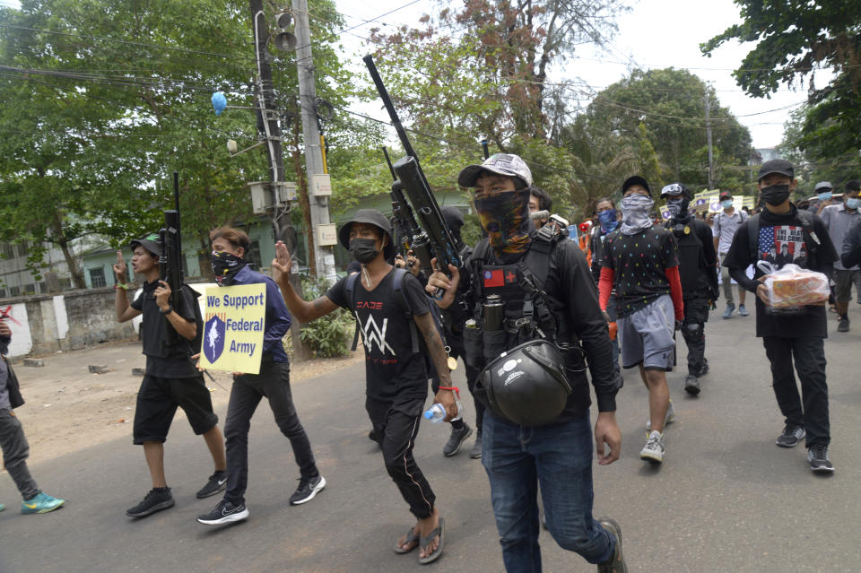 ADDS INFORMATION ON THE SIGN - Anti-coup protesters march with homemade air rifles as one of them holds sign showing support for a civilian-formed federal army during a protest march in Yangon, Myanmar, Saturday, April 3, 2021. Threats of lethal violence and arrests of protesters have failed to suppress daily demonstrations across Myanmar demanding the military step down and reinstate the democratically elected government. (AP Photo)