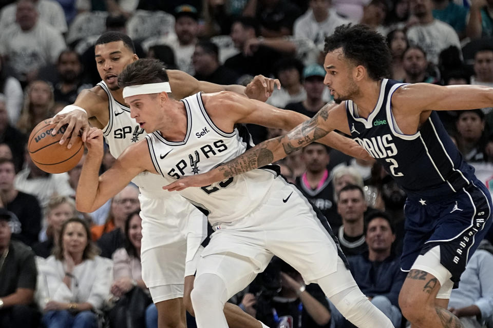 San Antonio Spurs center Victor Wembanyama, left, and forward Zach Collins, center, work against Dallas Mavericks center Dereck Lively II (2) for the ball during the first half of an NBA basketball game in San Antonio, Wednesday, Oct. 25, 2023. (AP Photo/Eric Gay)