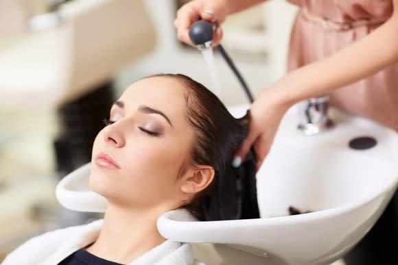 A woman has her hair washed in a hair-washing sink