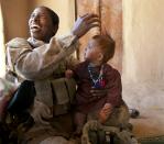 BOLDOC, AFGHANISTAN - NOVEMBER 23: (SPAIN OUT, FRANCE OUT, AFP OUT) Master Sargent Cherelle Peters-Williams, US Marine with the FET (Female Engagement Team) 1st Battalion 8th Marines, Regimental Combat team II plays with an Afghan baby girl during a village medical outreach on November 23, 2010 in Boldoc, in Helmand province , Afghanistan. There are 48 women presently working along the volatile front lines of the war in Afghanistan deployed as the second Female Engagement team participating in a more active role, gaining access where men can't. The women, many who volunteer for the 6.5 month deployment take a 10 week course at Camp Pendleton in California where they are trained for any possible situation, including learning Afghan customs and basic Pashtun language. (Photo by Paula Bronstein/Getty Images)