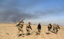 Rapid Response forces members cross farm land during a battle with Islamic State's militants south west of Mosul, Iraq February 24, 2017. REUTERS/Zohra Bensemra