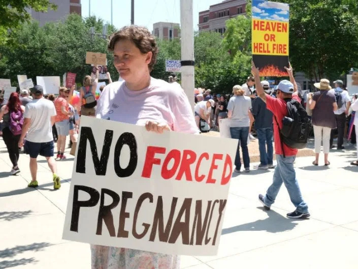 A protestor holds a sign reading 