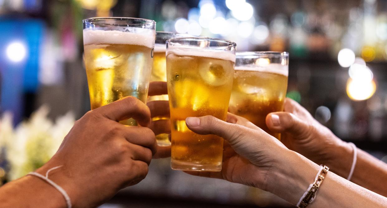 A group of people cheers with alcohol  in their hands.