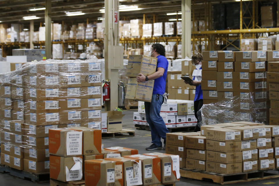 FILE - In this April 7, 2020, file photo, workers carry boxes at Oklahoma's Strategic National Stockpile warehouse in Oklahoma City, in Oklahoma City. States are spending billions of dollars stocking up on medical supplies like masks and breathing machines during the coronavirus pandemic. An Associated Press survey of all 50 states found a hodgepodge of public information about the purchase of masks, gloves, gowns and other hard-to-get equipment for medical and emergency workers. (AP Photo/Sue Ogrocki, File)