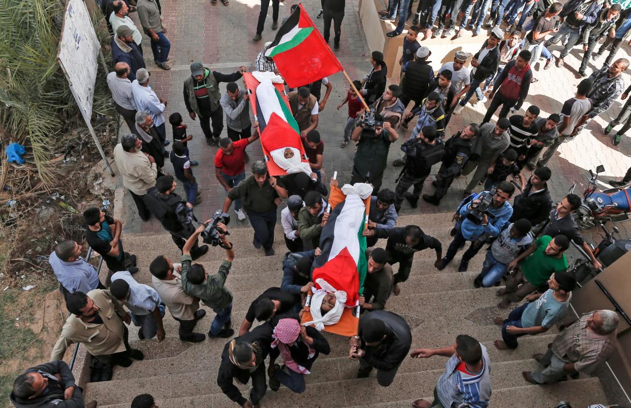 Palestinian mourners carry the bodies, draped in their national flag, of two of the three teenagers who were killed in an Israeli strike during their funeral in Deir el-Balah in the central Gaza Strip Photo: MAHMUD HAMS/AFP/Getty Images: MAHMUD HAMS/AFP/Getty Images